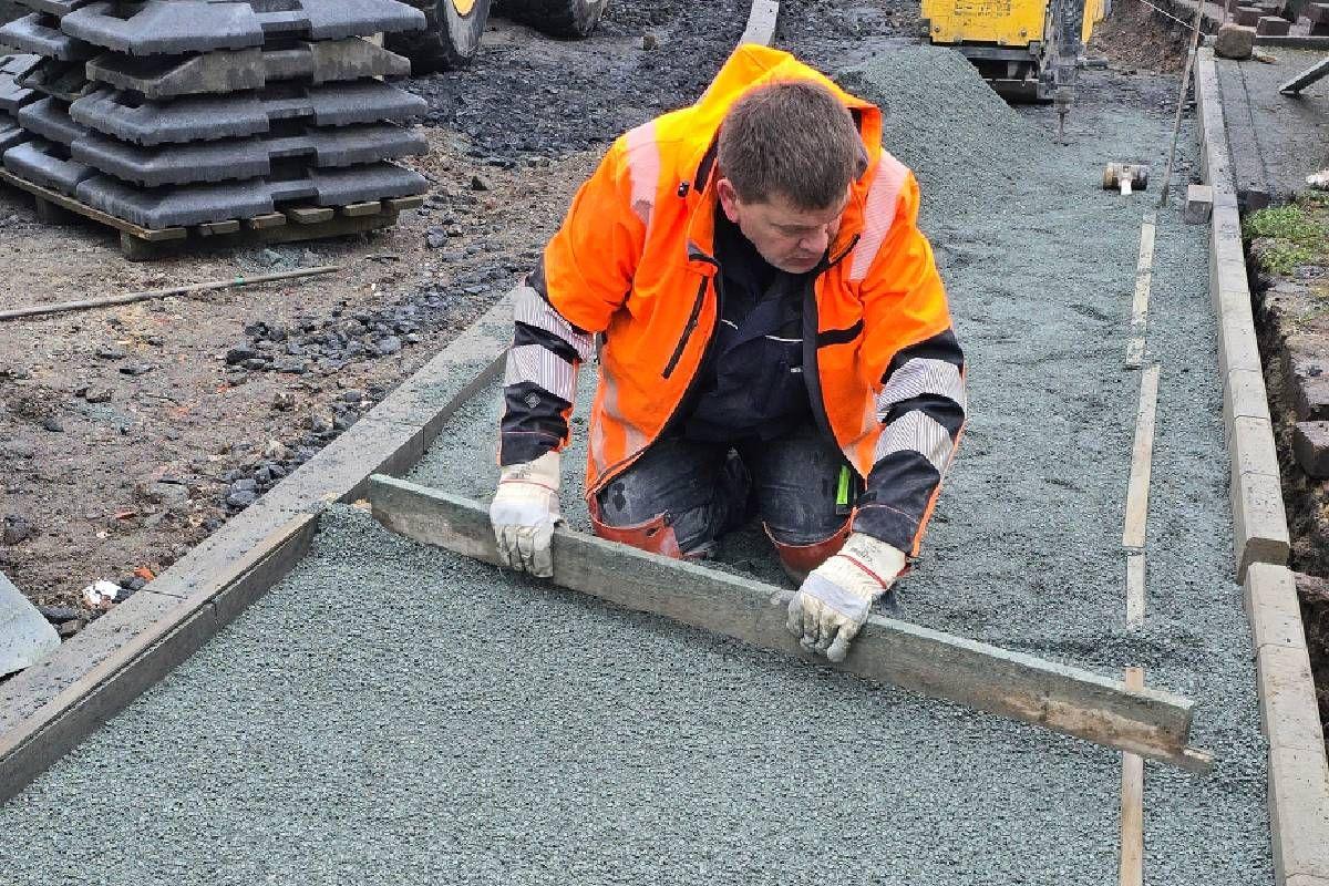 Unser Kollege stellt sicher, dass das Pflasterbett eben ist, damit die Pflastersteine höhengerecht verlegt werden können.
