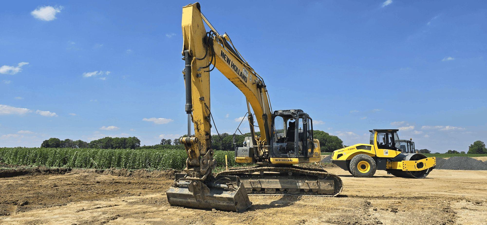 New Holland Bagger am Windpark Nordick – im Hintergrund ein Walzenzug.