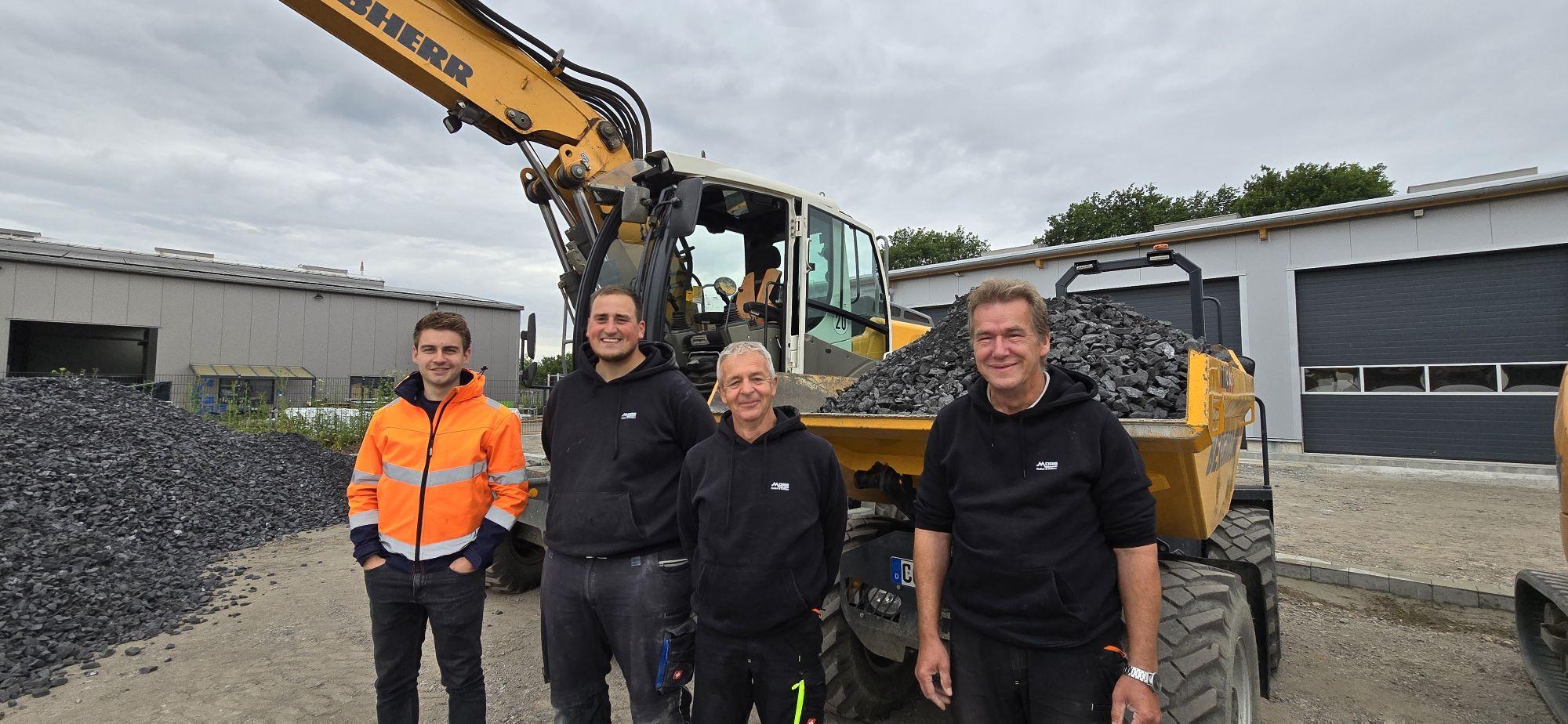 Arnd, Max, Mario und Martin vor einem Bagger und einem Dumper.